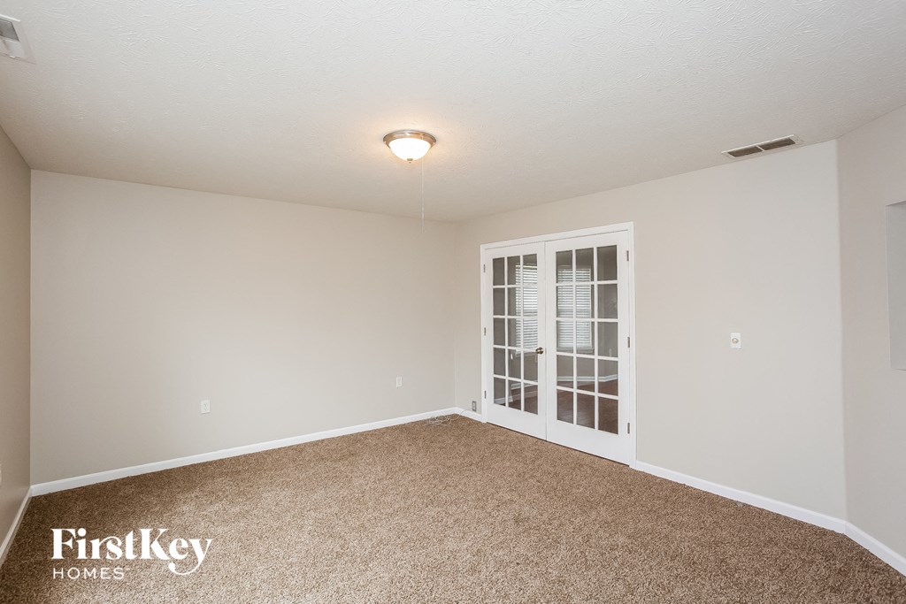 A carpeted room with a window and a FirstKey Homes logo.