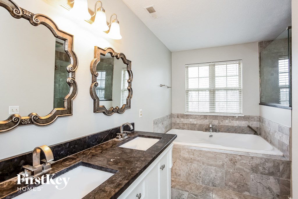 A bathroom with a black marble countertop and a large mirror above it.
