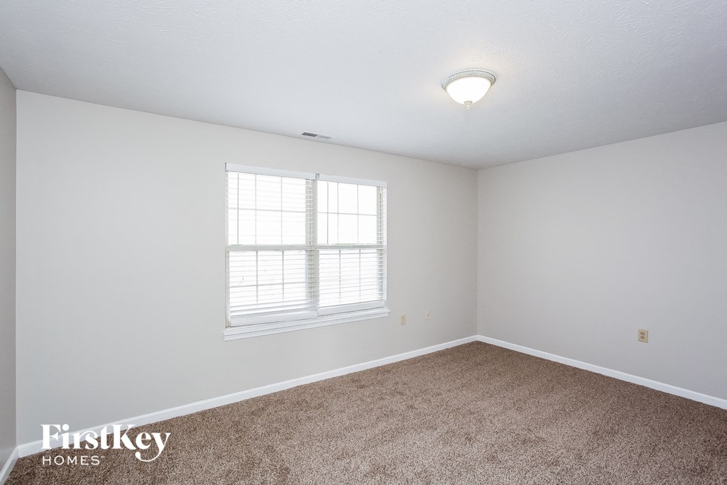 A room with a window and carpeted floor.