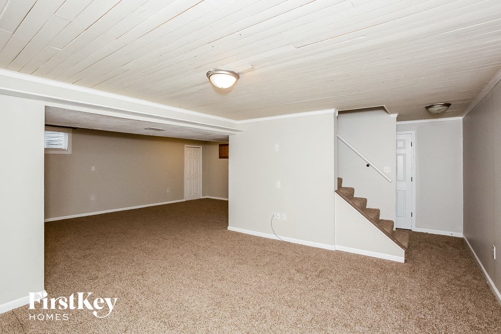 A spacious room with a staircase leading to the second floor.