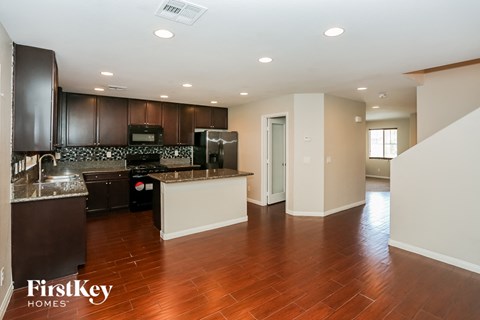 A kitchen with dark brown cabinets and a counter top with a sink.