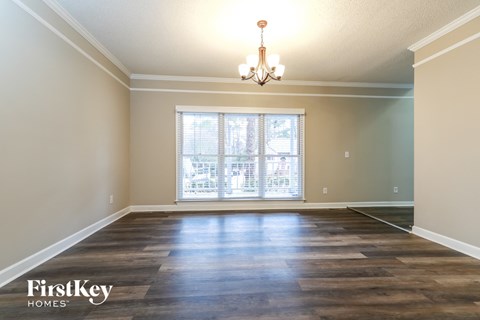 an empty living room with a window and a chandelier