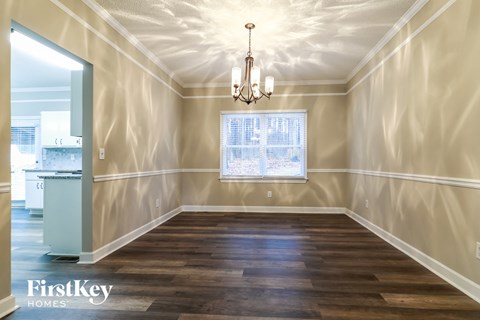an empty dining room with a window and a chandelier