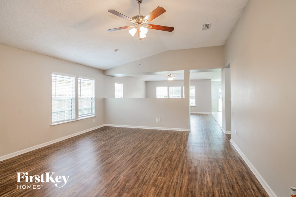 A spacious room with a wood floor and a ceiling fan.
