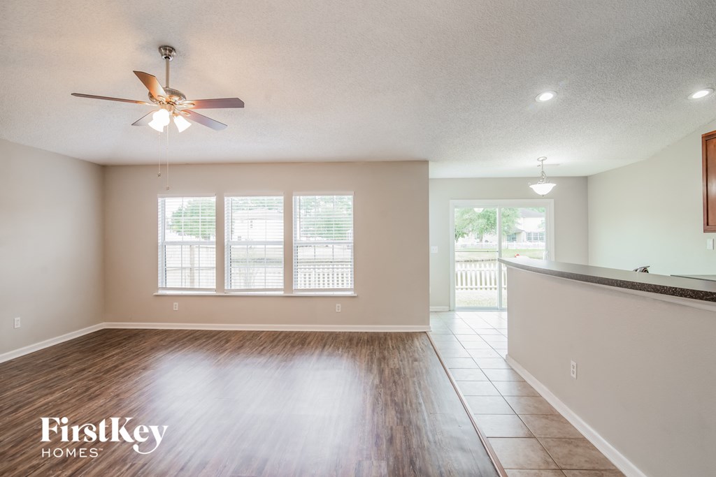 A spacious room with a ceiling fan and wooden flooring.