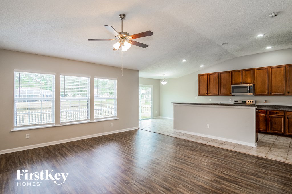 A spacious kitchen and living room with wood flooring and a ceiling fan.