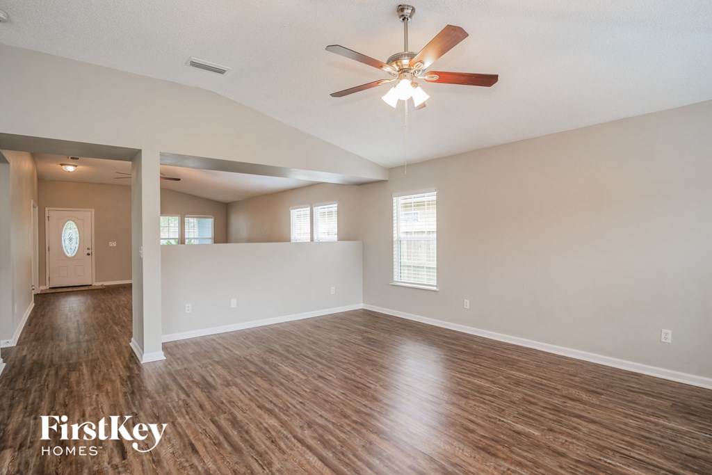 A spacious room with wooden floors and a ceiling fan.