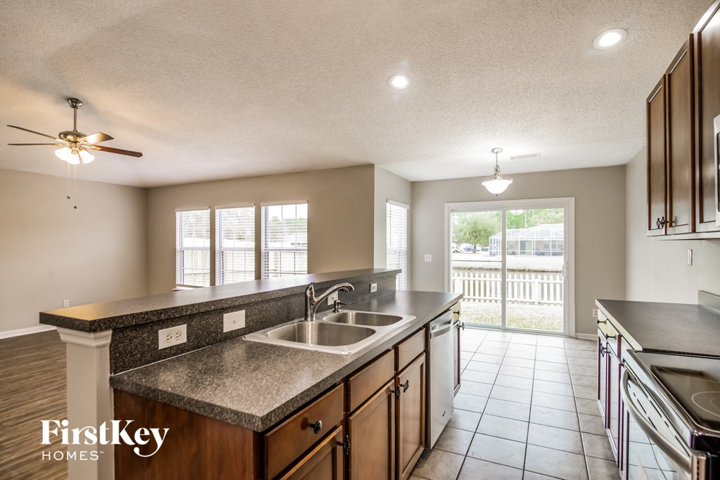 A kitchen with a sink, stove, and a ceiling fan.