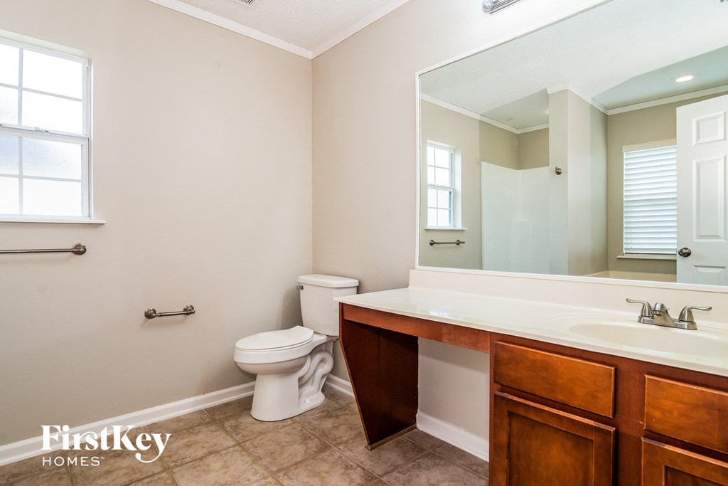 A bathroom with a toilet, sink and mirror.