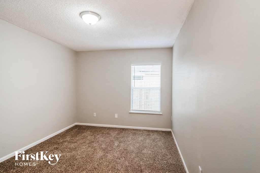 A room with a carpeted floor and a window with blinds.
