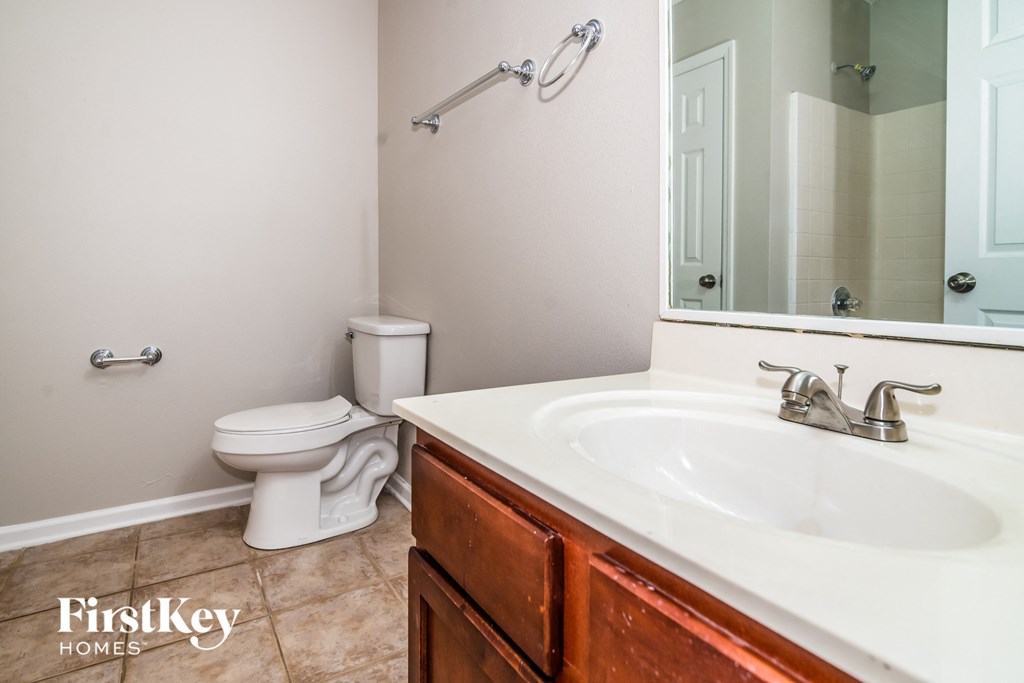 A bathroom with a toilet, sink, and mirror.