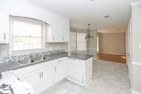 A kitchen with white cabinets and a marble floor.