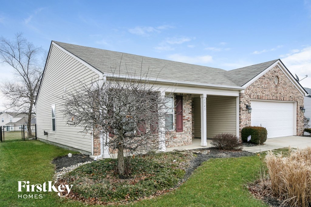 A house with a garage and a tree in front of it.