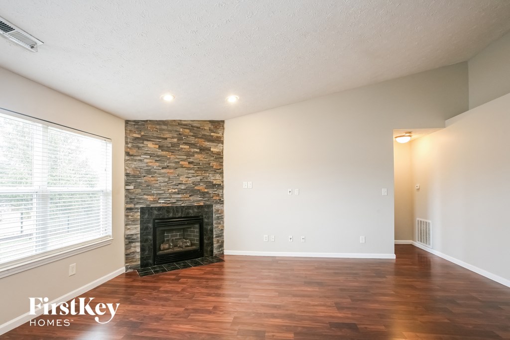 A room with a stone fireplace and wooden floors.