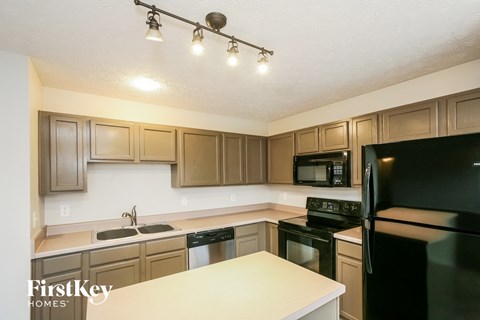 A kitchen with a black refrigerator and brown cabinets.