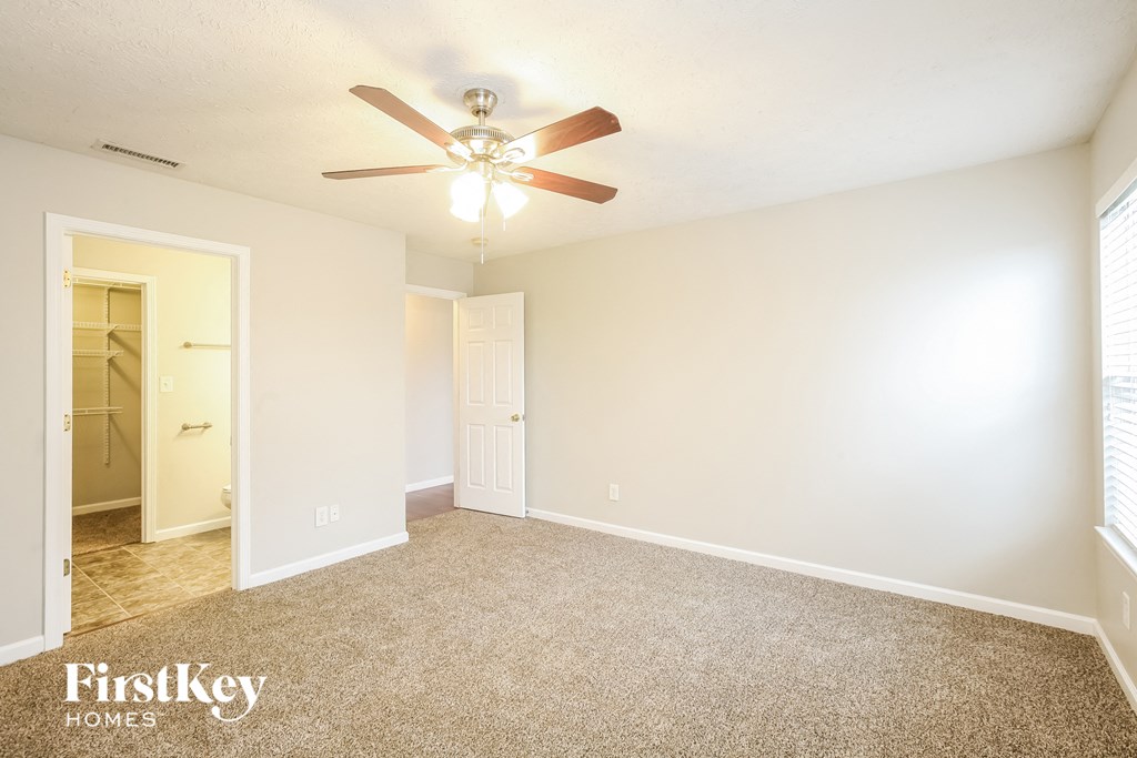A spacious room with a ceiling fan and carpeted floor.
