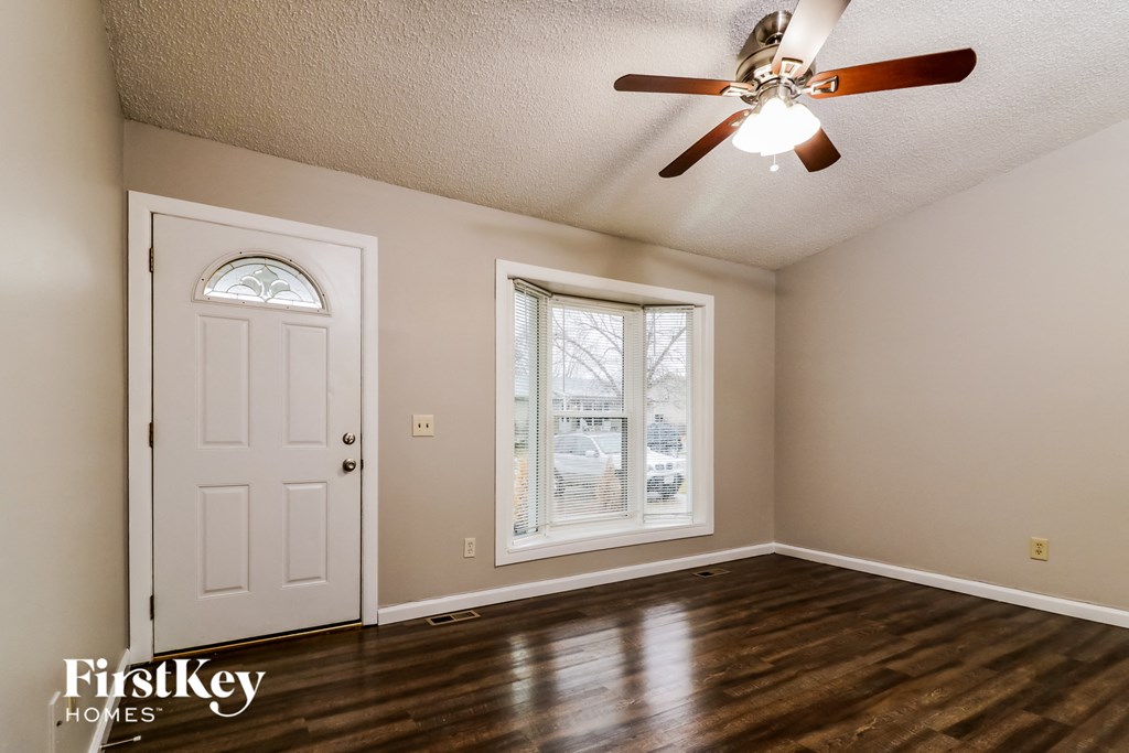an empty living room with a ceiling fan and a white door