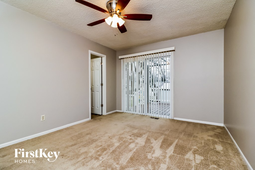 an empty living room with a ceiling fan and a sliding glass door