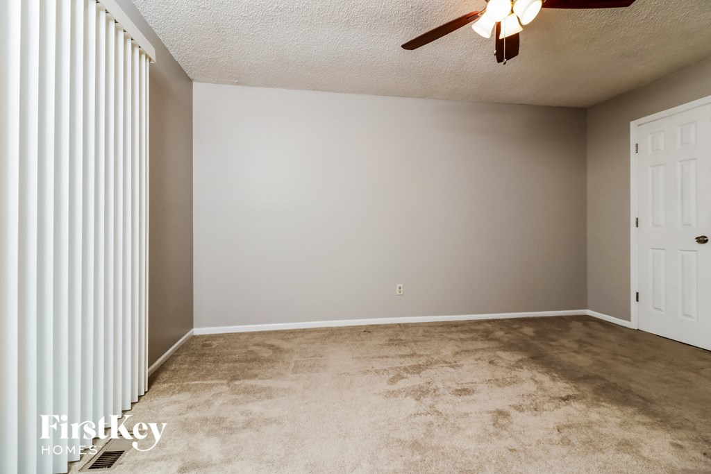 a empty living room with a ceiling fan and a closet