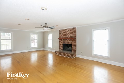 a living room with a brick fireplace and wooden floors and a ceiling fan
