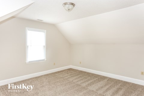 a bedroom with white walls and carpet and a window