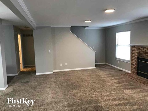 A spacious living room with a carpeted floor and a fireplace.