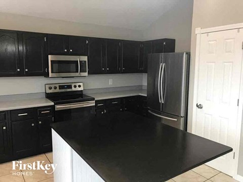 A kitchen with black cabinets and a stainless steel refrigerator.