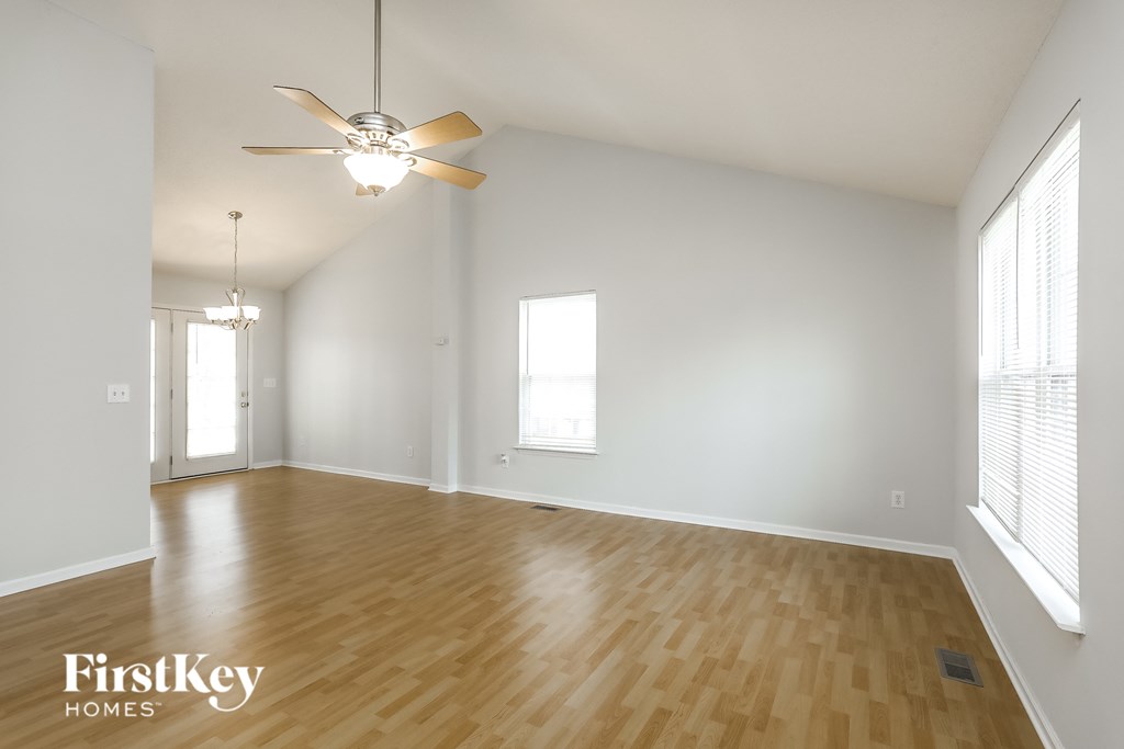 an empty living room with wood floors and a ceiling fan