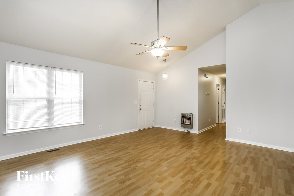an empty living room with wood floors and a ceiling fan