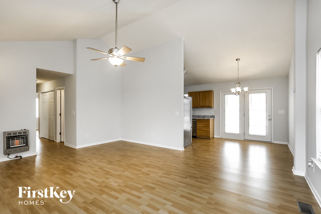 an empty living room with wood flooring and a ceiling fan