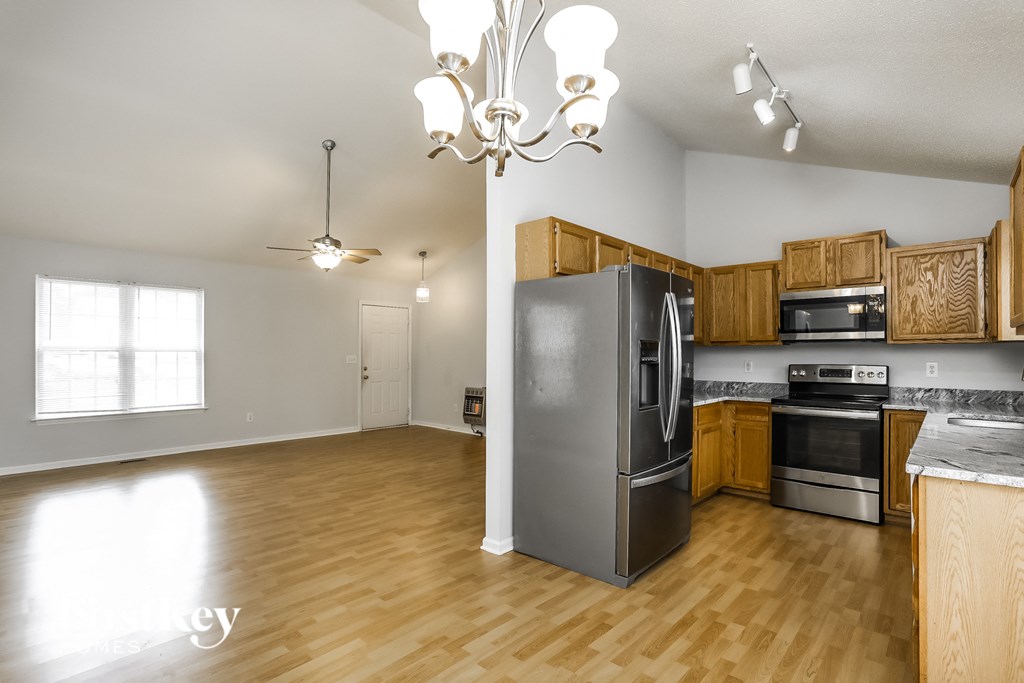an empty kitchen with wood flooring and stainless steel appliances