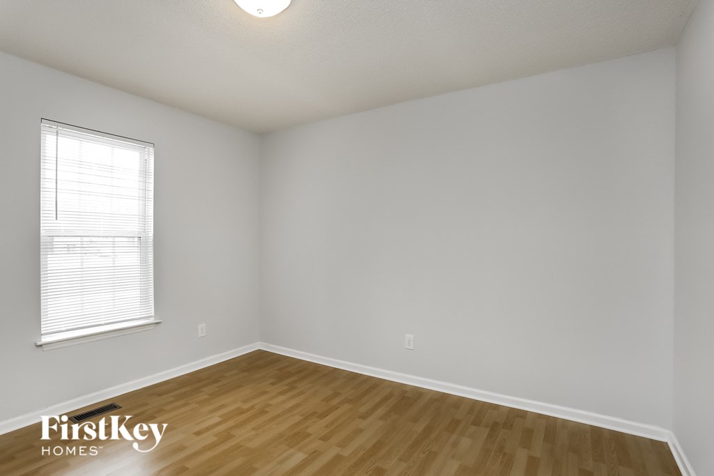 a bedroom with wood flooring and white walls and a window