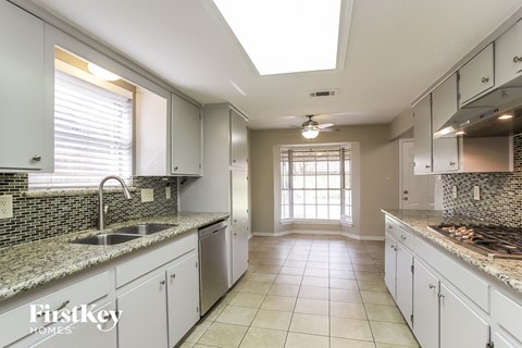 A kitchen with white cabinets and a marble countertop.