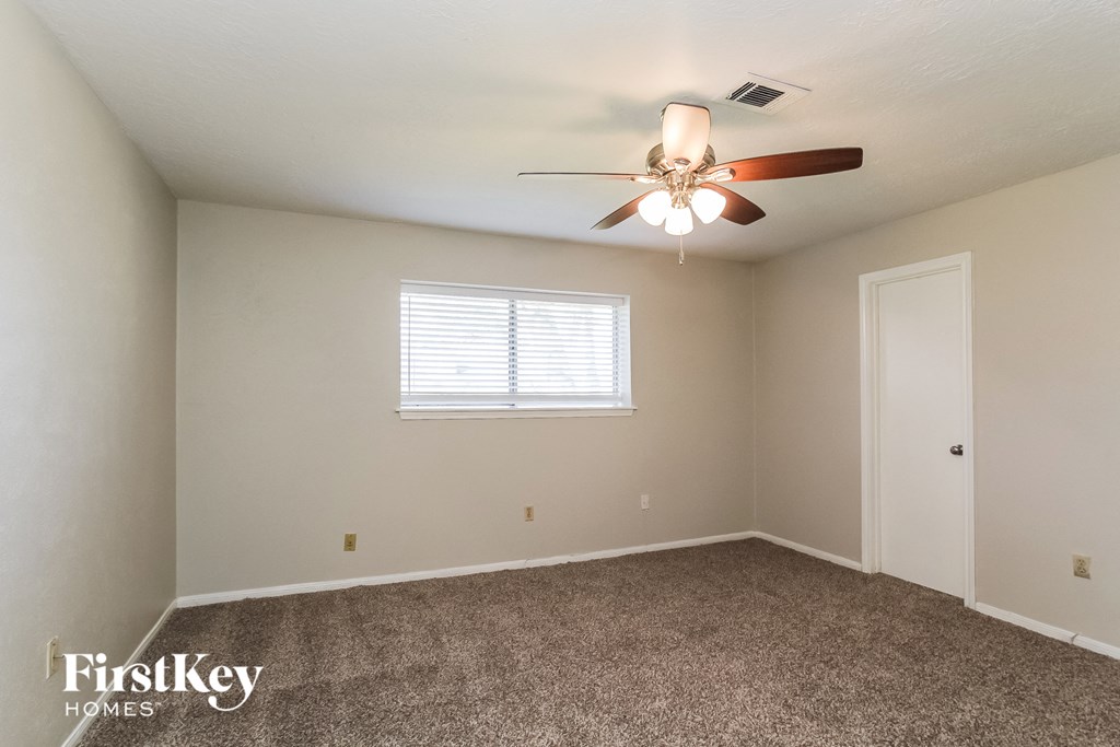 A room with a ceiling fan and a window with blinds.