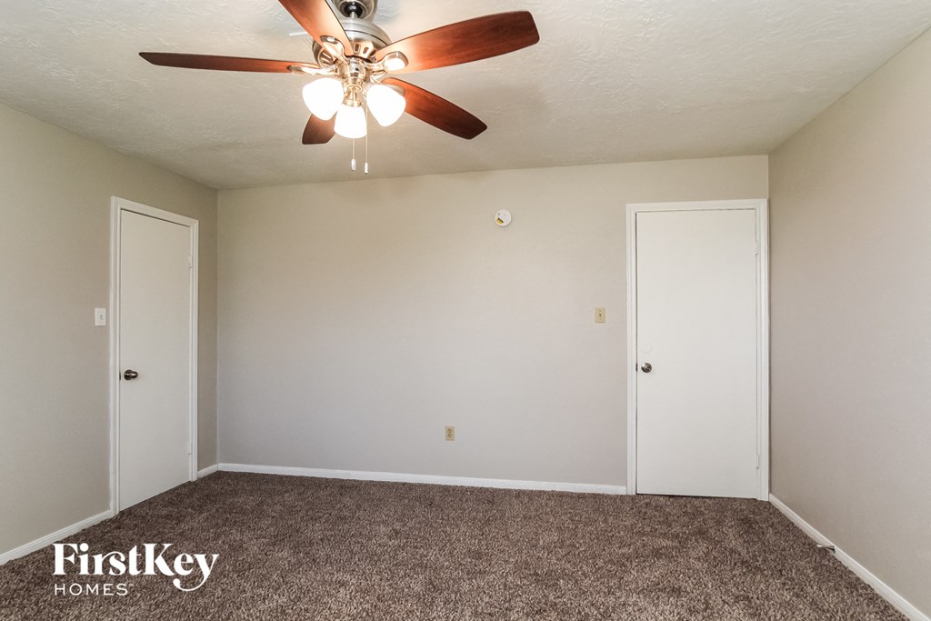 A room with a ceiling fan and two doors.