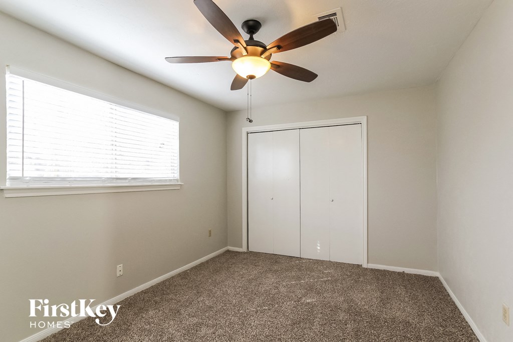A room with a ceiling fan and a window with blinds.