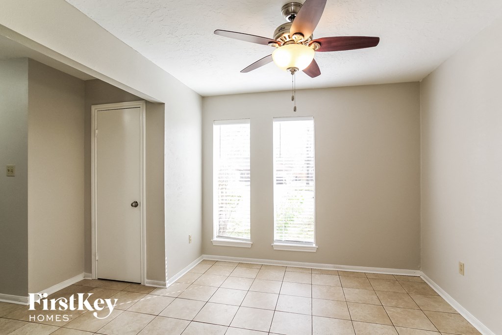 A room with a ceiling fan and a door leading to another room.