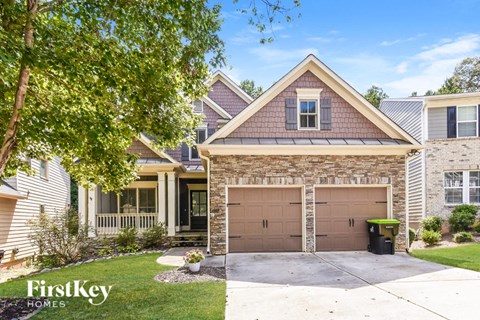 A house with a garage and a tree in front of it.