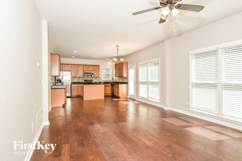 A spacious kitchen with wooden floors and a ceiling fan.