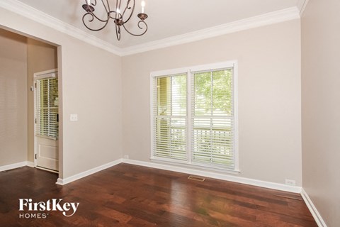 A room with a chandelier and a window with blinds.