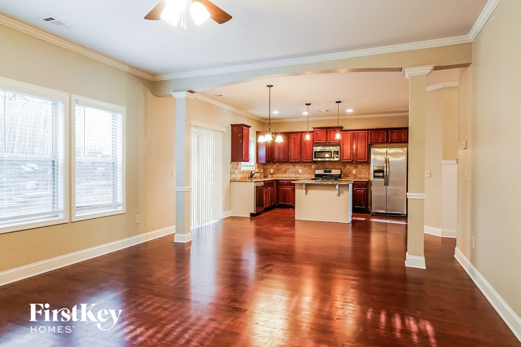 A spacious kitchen and living room with wooden floors and a ceiling fan.