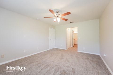 a spacious living room with carpet and a ceiling fan