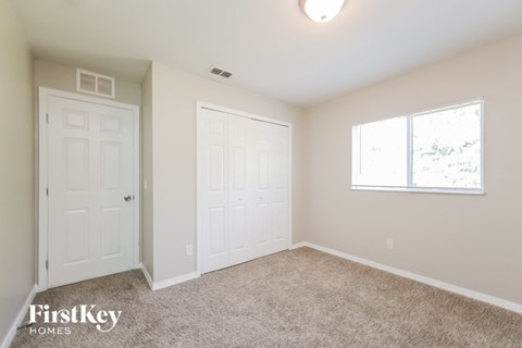 an empty bedroom with two doors and a window