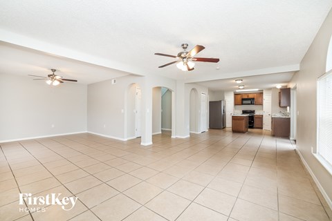 a spacious living room with tile flooring and a ceiling fan