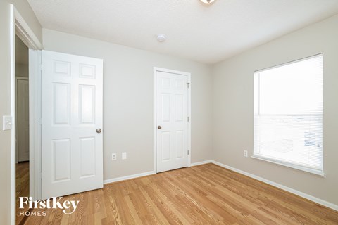 a bedroom with two doors and a window and a wood floor