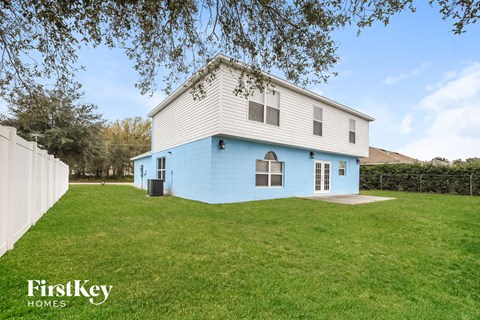 a blue and white house with a grassy yard and a white fence