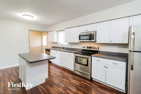 A kitchen with white cabinets and a wooden floor.
