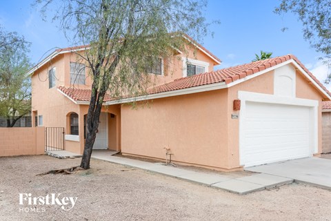a pink house with a white garage door and a tree