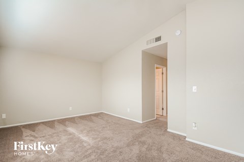 a spacious living room with carpet and a door to a hallway