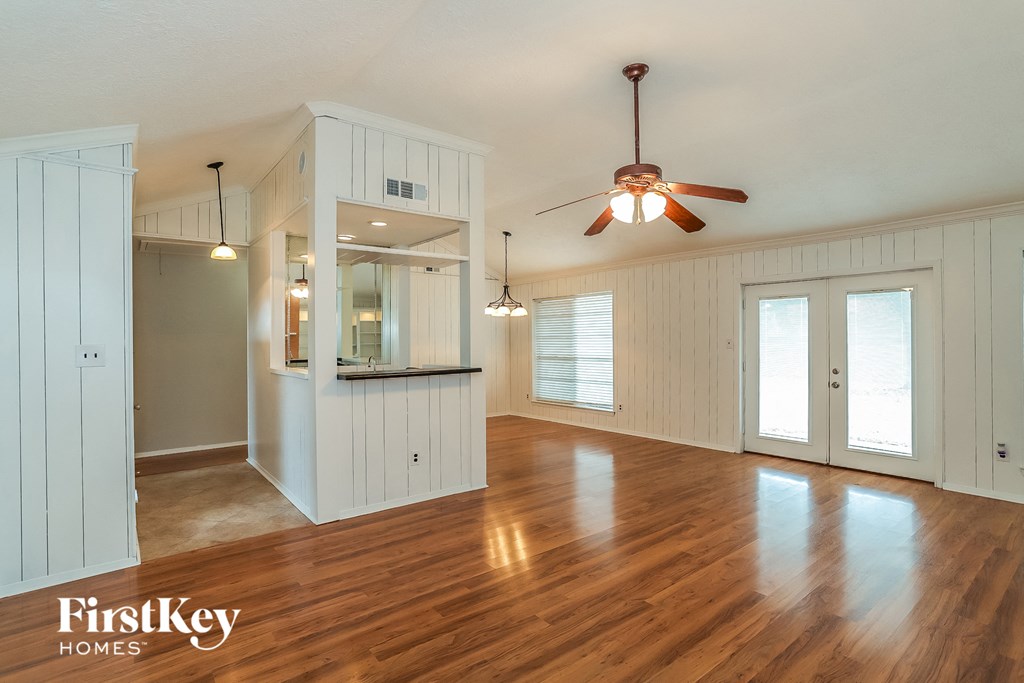 A spacious room with wooden floors and a ceiling fan.